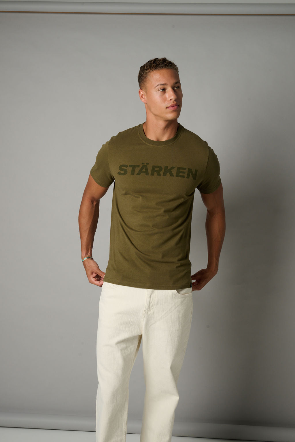 Man wearing a green t-shirt with 'Stärken' text against a gray background